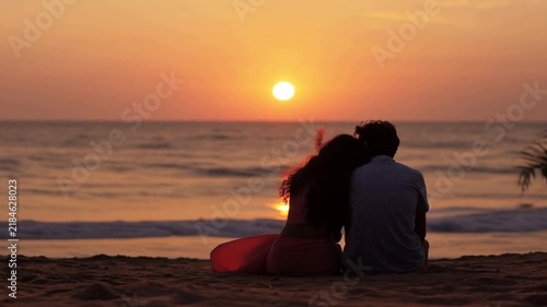 Couple lovers sitting at a beach watching sunset