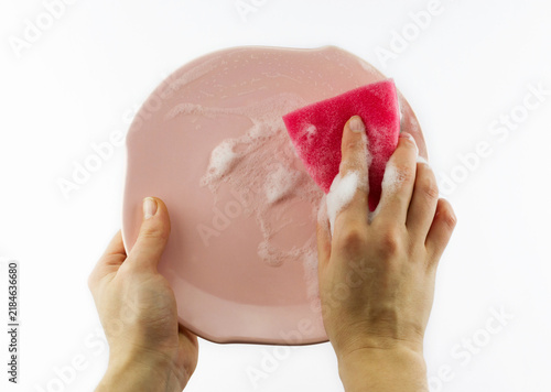 Fotografie Close view of hands scrubbing a pink plate with a red sponge and soap foam, show