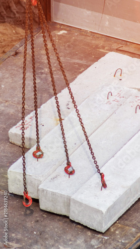 Industrial chains with hooks attaching to concrete road parts ready for lifting, heavy construction materials transportation, urban infrastructure development, vertical photo