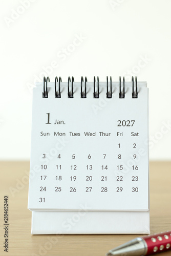 January first 2027 calendar month with pen on a wooden desk and white background. Copy space. New year plan, goal, and resolution concept.