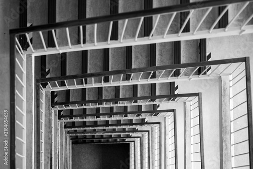 Foto Black and white top-down view of a multistory square stairwell with repeating railings and steps, creating geometric perspective, deep symmetry and an abstract architectural pattern