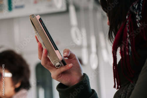 Close-up of a woman using a smartphone inside a public train during commute.