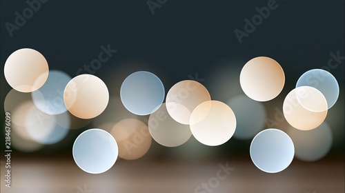 Bokeh lights in warm beige and soft blue colors create a glowing horizontal pattern against a dark background.