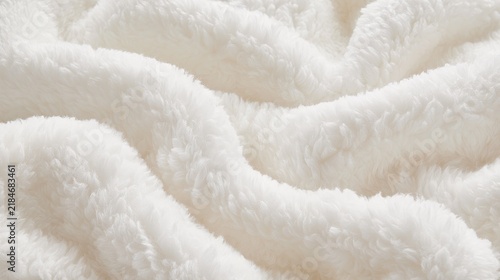 Close-up of soft white fluffy fleece fabric with gentle folds. Useful as a cozy background texture for textile and fashion projects.
