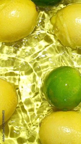 Whole citrus fruits falling and splashing through clear water, top view slow motion
