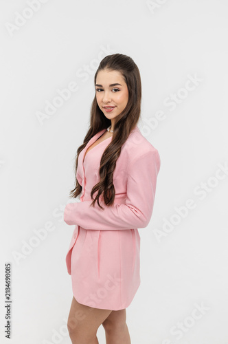 A beautiful schoolgirl in a classic pink suit against a white background.