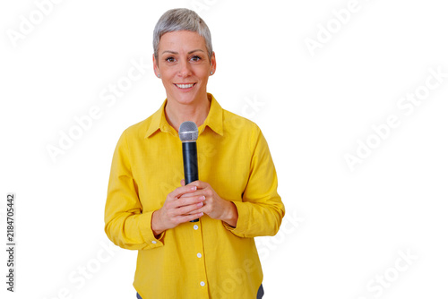 Canvastavla Mature woman with gray hair holding a microphone and smiling, giving a presentat