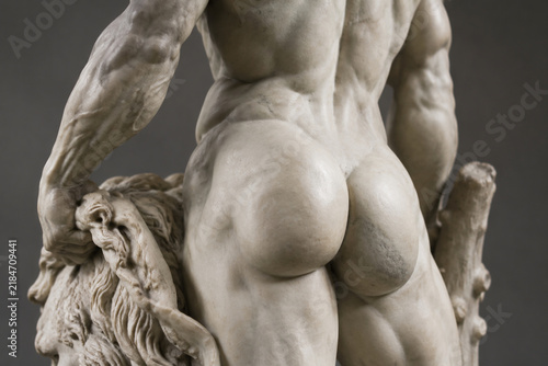 Classical marble statue of Hercules, focus on the sculpted muscles of the lower back.