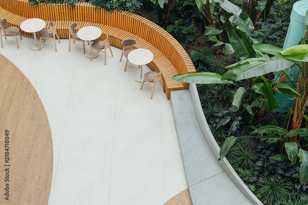 Obraz premium Outdoor seating area with tables and chairs next to a lush green plant display