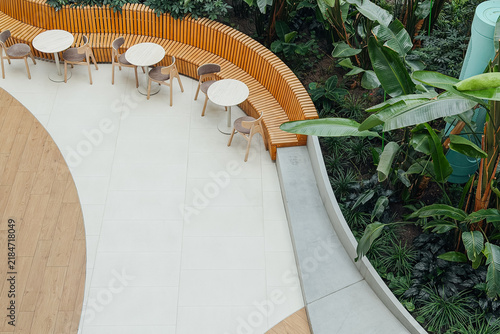 Outdoor seating area with tables and chairs next to a lush green plant display