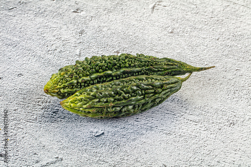 Konstfotografi Two fresh green bitter melons with bumpy texture on light gray textured surface,