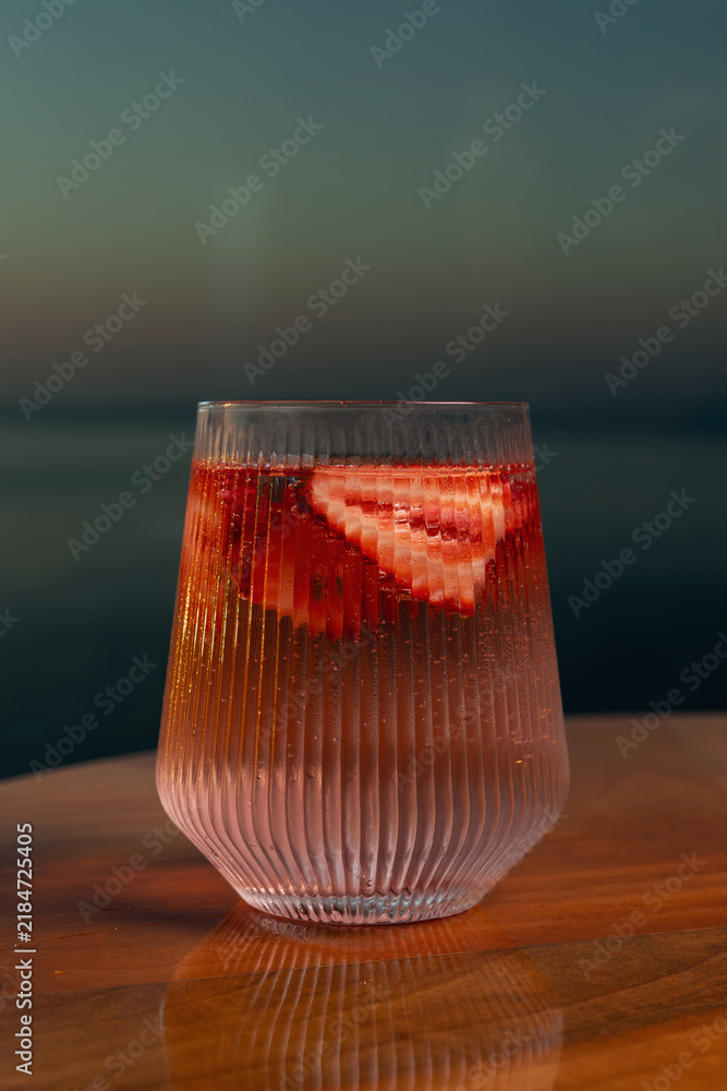 Obraz premium Strawberry lemonade with lime and fresh mint overlooking the sea at sunset 