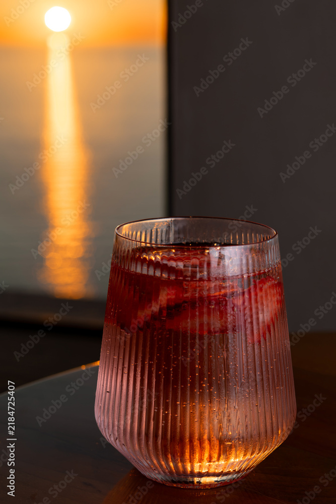 Fototapeta premium Strawberry lemonade with lime and fresh mint overlooking the sea at sunset 