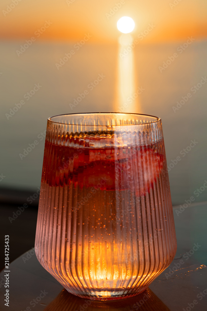 Obraz premium Strawberry lemonade with lime and fresh mint overlooking the sea at sunset 
