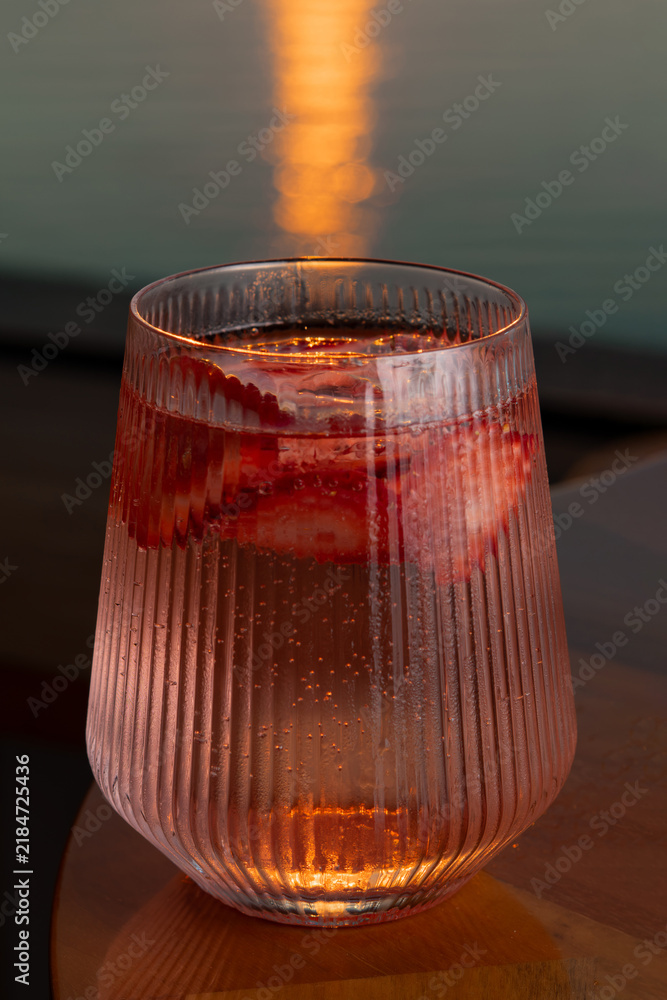 Obraz premium Strawberry lemonade with lime and fresh mint overlooking the sea at sunset 