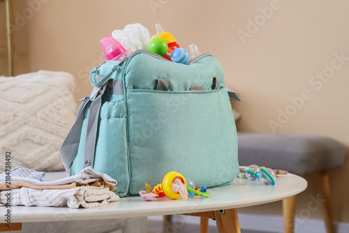 Baby bag with accessories and rattles on table in living room