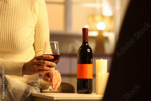 Canvastavla Woman taking glass of red wine from table at home late in evening