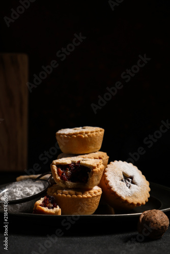 Canvastavla Plate of tasty Christmas mince pies with sugar powder and nuts on black backgrou