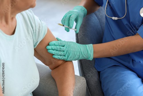 Senior woman receiving vaccine from doctor at home, closeup