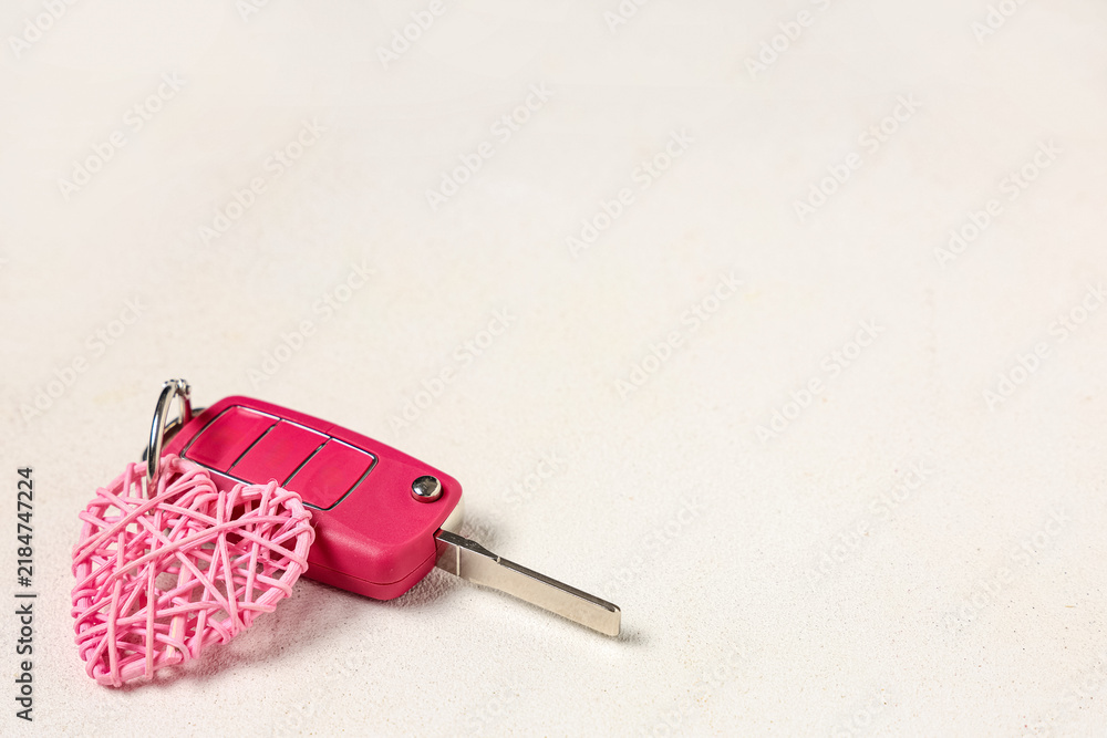 Obraz premium Car key with pink heart on white background