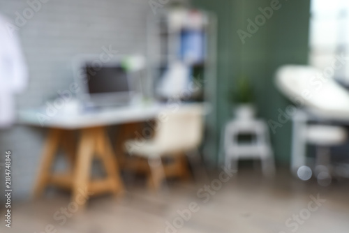 Blurred view of modern medical office with doctors workplace and shelf unit