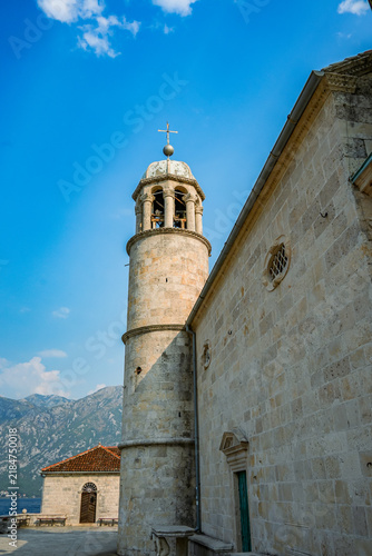 Historic stone bell tower against mountains and blue sky