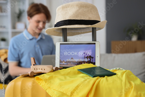 Tablet computer with open page of online booking service and travel accessori...