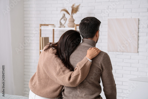 Young couple hugging at home on autumn day, back view