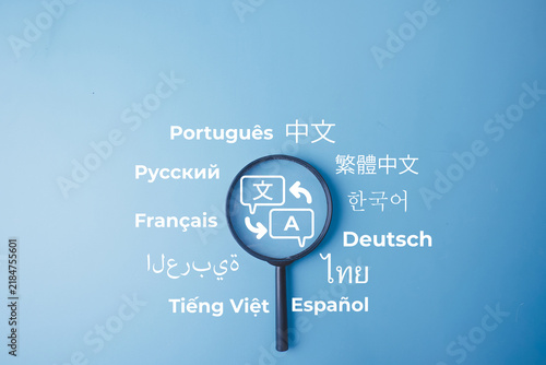 Magnifying glass with a translation icon and various language words on a blue background. Concept of multilingual communication, language learning, global localization, and translation service.