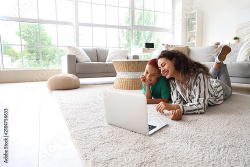 Little African-American boy with his mother watching cartoons on floor at home