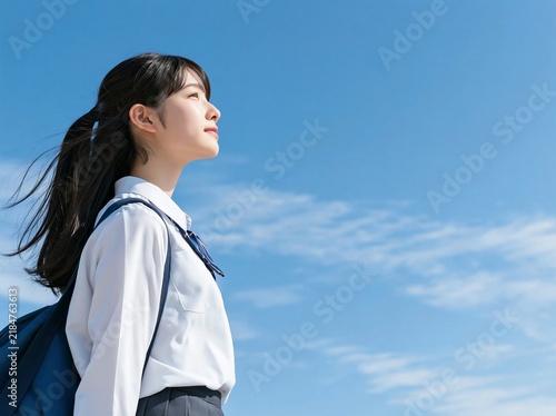 Fototapeta 青空を背景に未来の夢に向かって澄んだ瞳で遠くを見つめる女子学生の横顔