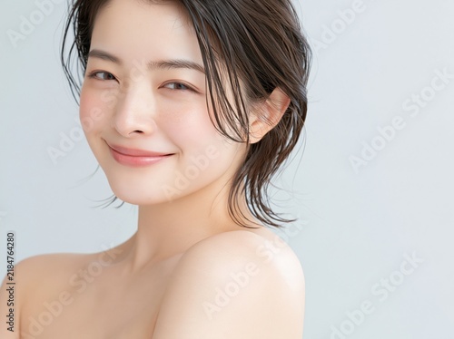 Tapety artystyczne 髪を軽くかき上げ爽やかな笑顔を見せる素肌の美しい女性