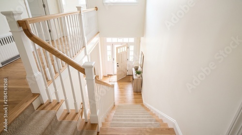 Elegant residential interior showcasing pristine finish carpentry on a grand wooden staircase and bright entryway