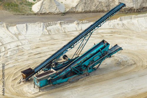 Aerial view of a large sand and gravel mine featuring industrial conveyor belt equipment operating on sandy terrain in Poland.