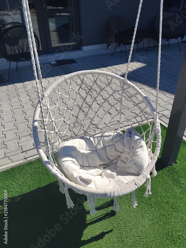 Cozy macrame hanging swing chair with cushion on patio