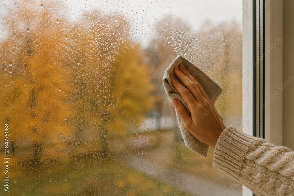 Fototapeta premium Wiping fogged window glass with cloth on autumn day