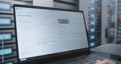 Foto IT Engineer Reviews Infrastructure Dashboard Showing Firewall Status, SSL Certificate Validity, DDoS Protection, Cooling Fan Speed, Server Temperature and Network Traffic Across Data Center Systems