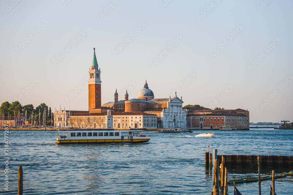 Fototapeta premium View of San Giorgio Maggiore Island across the Venetian Lagoon with a traditional public water bus passing through the waters of Venice, Italy.