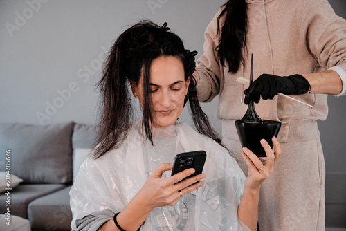 Cuadro en lienzo Woman getting hair colored using smartphone for entertainment