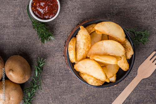 Foto Potatoes cut into pieces and fried, served in a black bowl on a black background