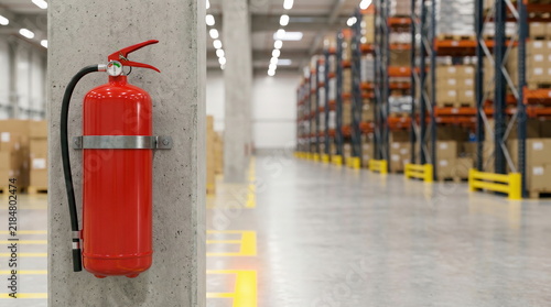 Fire extinguisher mounted on concrete pillar in modern warehouse with racks, for safety and emergency preparedness.