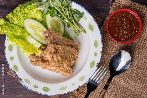 Obraz na plátne Fried free-range chicken served with lettuce, cucumber, and watercress as accompaniments, plated and photographed against a gray background