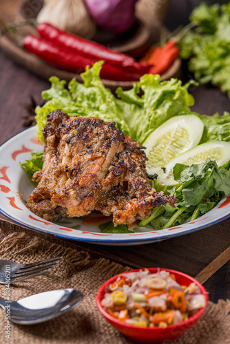Фотография Grilled *Tuwuk* free-range chicken—accompanied by lettuce, cucumber, and watercress—is plated and photographed against a gray background