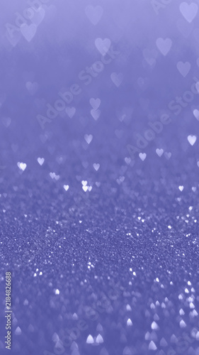 Abstract purple glitter background with soft heart shape bokeh light. Vibrant, romantic, festive backdrop for celebration, love concept