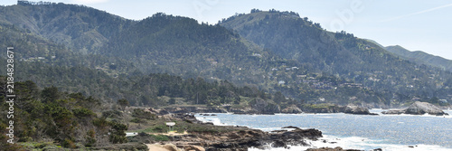 Bild auf Leinwand Wide panoramic view across California's rugged Pacific coastline, combining rocky ocean headlands, sparkling blue water and densely wooded coastal mountains dotted with hillside homes