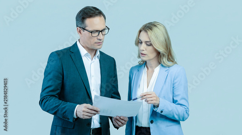 Business Colleagues Reviewing Documents Together Against Light Blue Background