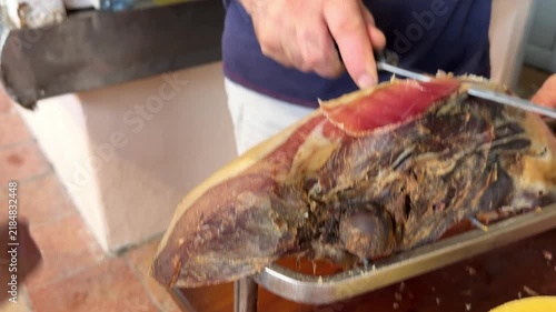 Traditional Montenegrin prsut being freshly sliced with a knife at a local food market in Kotor, Montenegro. 