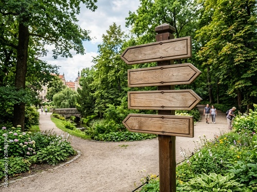 Blank Wooden Signpost In A Lush Green Park With Paths Leading To Distant Buildings