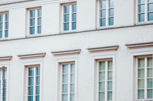 Fotografie Rows of windows with sharp spikes on the ledges of a white building exterior wal