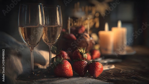 Elegant romantic table setting with two glasses of wine, fresh red strawberries, and warm glowing candles